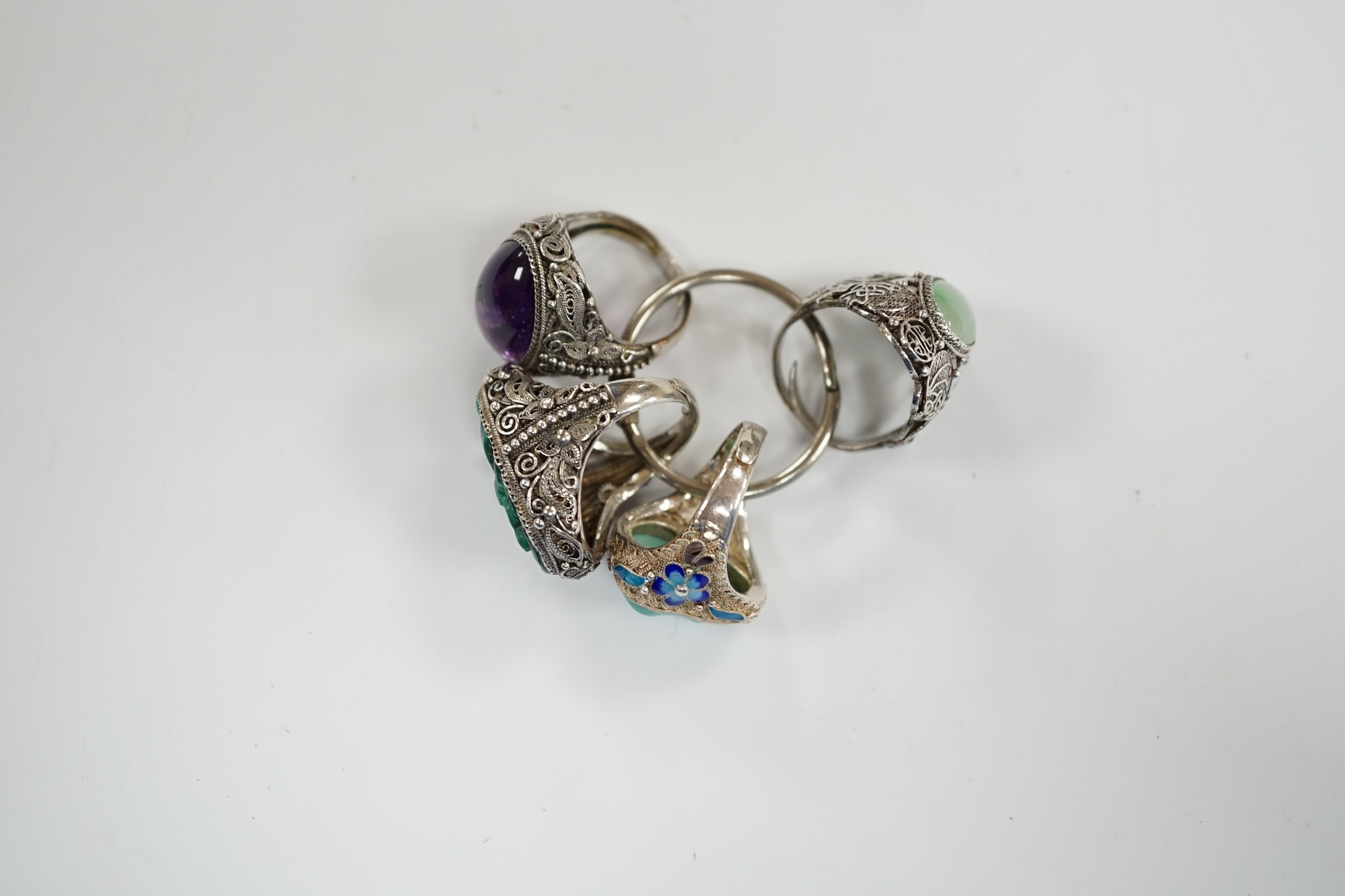 Four assorted Chinese white metal filigree and gem set rings, including turquoise and amethyst.